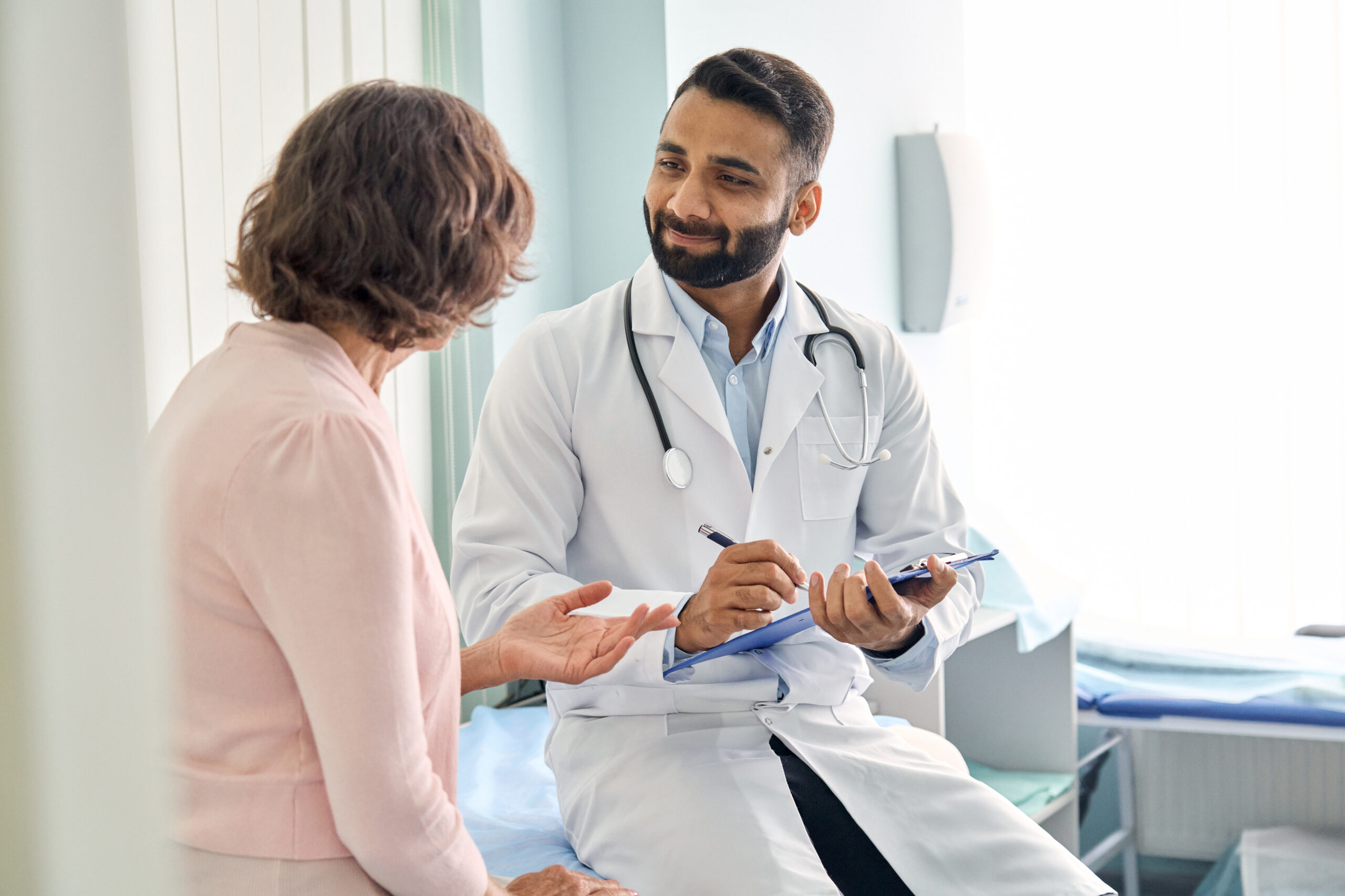 A male doctor talks to a patient about her current prescriptions.